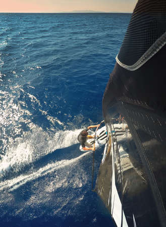 Windsurfing in sea. Perspective from above on sail towards the surfer.