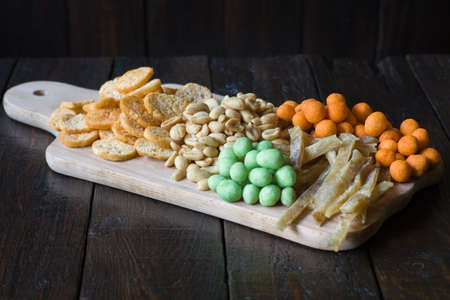 Snacks for beer on the table in the pub. Peanuts, peanuts in a shell, pieces of fish, crackers.の写真素材