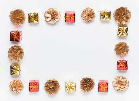 Christmas frame, pattern of pine cones and small gift boxes, on a white background. Top view....