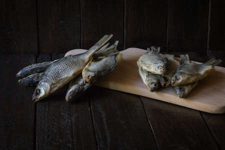 Dried fish on a wooden board and on a wooden background. Copy space. The concept of recreation,...