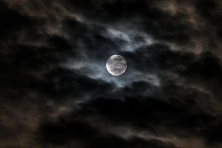 Full moon in the night sky in a cloudy hazeの写真素材