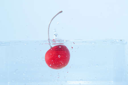 red cherry falling in waterの写真素材