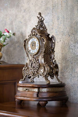 Metallic interior clock on a wooden stand