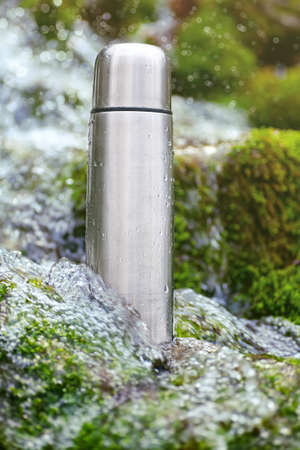 Stainless steel thermos is in the turbulent river waterの写真素材