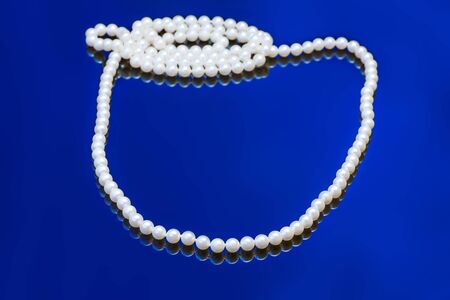Necklace with white pearl on a blue backgroundの写真素材