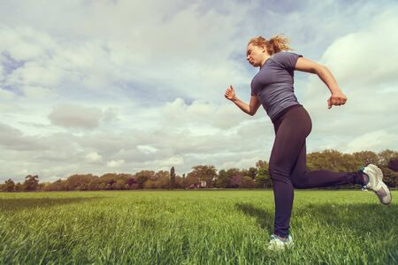Side view of a woman running on the grassの写真素材