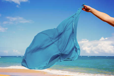 blue pareo shawls flowing in the wind on background of seaの写真素材