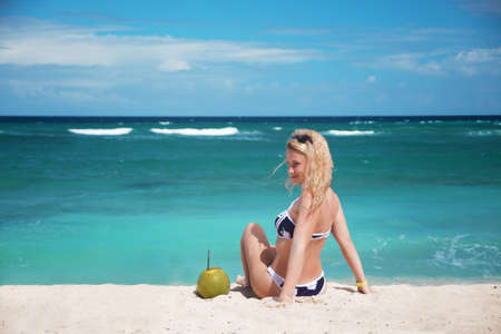 Young pretty girl in bikini with coco cocktail on the sandy caribbean beach. Azure sea. Vacation concept. Dominican Republicの写真素材