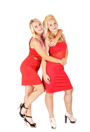 Couple smiling blonde girls in red dresses on high heels isolated on white background.  Lovely sistersの写真素材