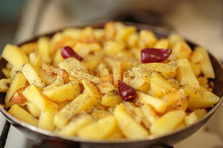 fried potatoes with red and black pepper in a frying pan. homemade food