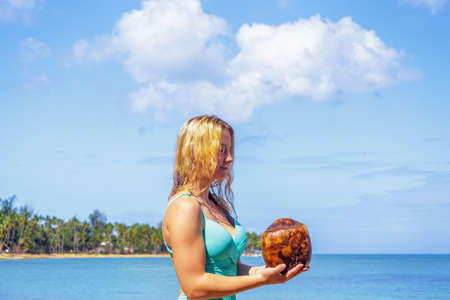 Young girl holding coconut on the beach