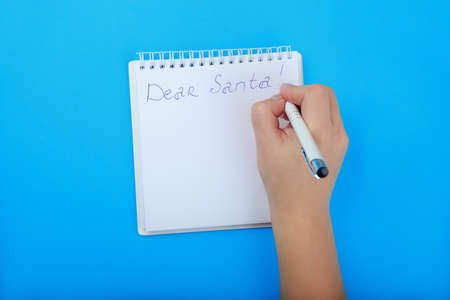 letter to Santa Claus in Notepad with space for list. children's hand writing a letter to Santa on...