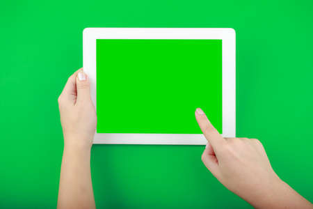 Digital Tablet and Hands on green Background. Finger shows something on empty screenの写真素材