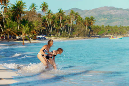 two girls friends play and frolic on a tropical beach. the concept of female friendshipの写真素材