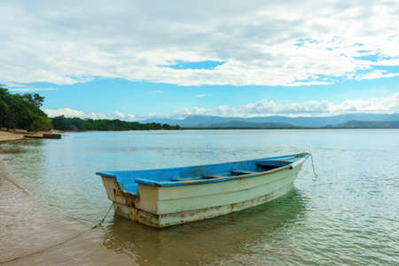 An old white blue empty wooden boat on the river Bankの写真素材