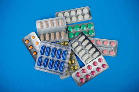 drug therapy, pharmaceutical branch, a group of different colorful pills in blister packs on blue...