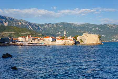 view from the sea to the old town of Budva on background of green mountains and stormy skyの写真素材