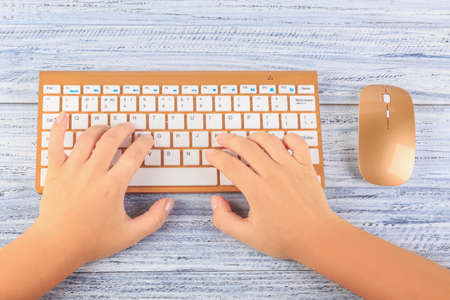 top view on female hands working typing on wireless gold keyboard and mouse on grey wooden backgroundの写真素材