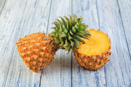 two halves of pineapple, cuteed ripe pineapple on light wooden backgroundの写真素材
