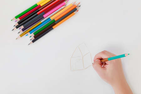hand drawing with color double-sided pencils on white background, female hand drawing the houseの写真素材