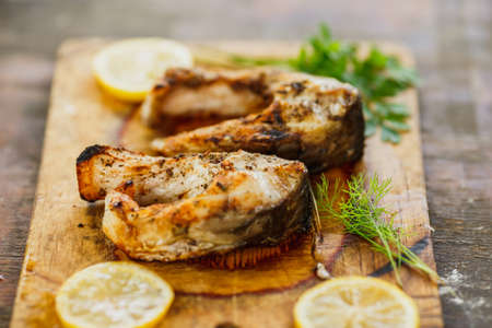 appetizing grilled fish pieces with parsley on the wooden boardの写真素材