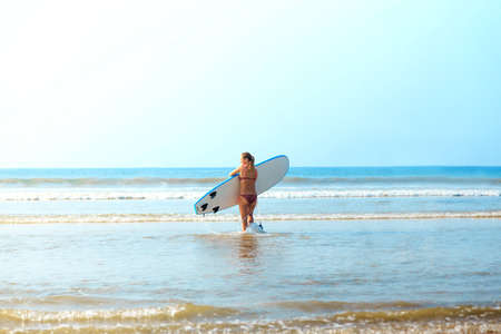 white blonde surfer girl  bikini with surfboard goes to seaの写真素材