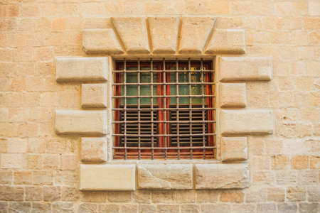 old window with bar on the stone wallの写真素材