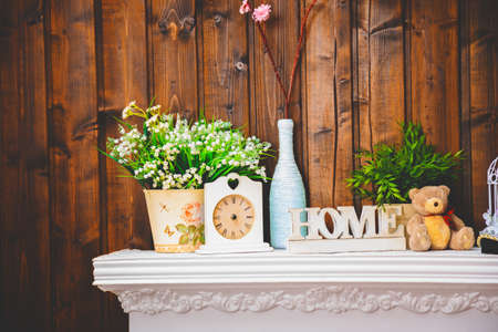 cozy home interior, clock, vase with flowers, toy bear and white home sign on wooden wall background,の写真素材