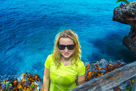 Happy smiling girl with curly hair in sunglasses on background of dark blue caribbean seaの写真素材