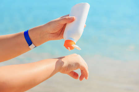 Women's hands apply a suntan lotion to the skin, protect from the sun.の写真素材