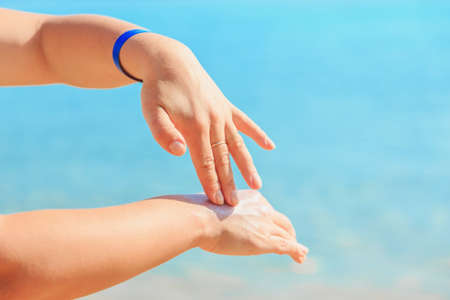 Women's hands apply a suntan lotion to the skin, protect from the sun.の写真素材