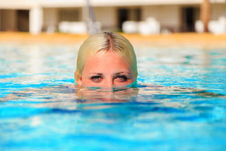 girl swimmer in swimming pool. head half in clear water, mermaid peeps out of the waterの写真素材