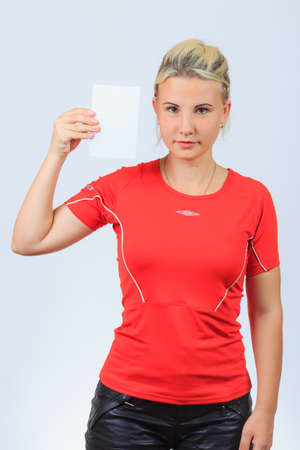 Young serious girl in sporty red shirt and black shorts holds blank brochure, booklet, pamphlet, leaflet with copyspaceの写真素材
