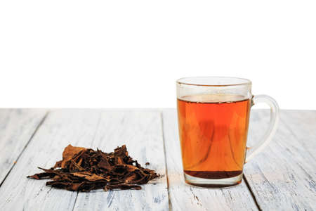 Cup of hot black tea and dried tea leaves on wooden table with place for copyspaceの写真素材