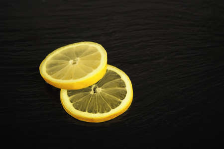 two fresh lemon slices on black backgroundの写真素材