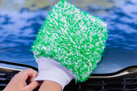 car cleaning with green fluffy washing mitten close up