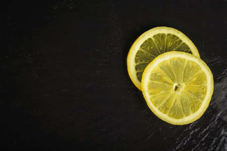 two fresh lemon slices on black background with copyspace on leftの写真素材