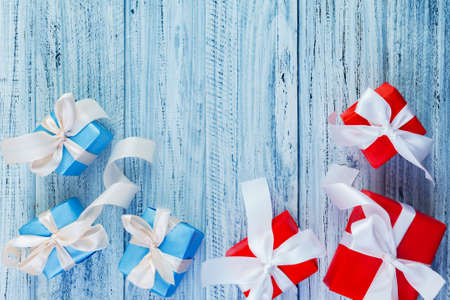 christmas or new year frame composition with red and blue presents packed with ribbons on light wooden background. Flat lay, top view, copy spaceの写真素材