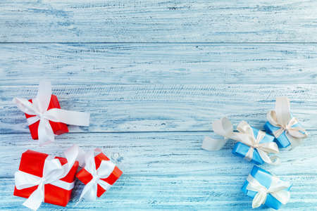 christmas or new year frame composition with red and blue presents packed with ribbons on light wooden background. Flat lay, top view, copy spaceの写真素材