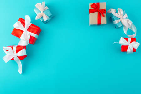 Holiday frame made of presents on blue background. Flat lay, top view, copy space