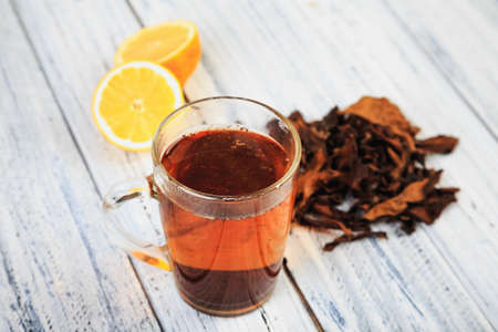 Cup of hot black tea, dried tea leaves and citrus halves on a light wooden backgroundの写真素材