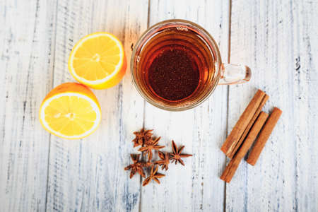 hot tea, cinnamon sticks, star anise and orange on light wooden background top viewの写真素材