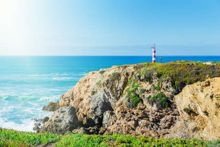 landscape with ocean, high rocks and lighthouse at the top of the mountain. Portugal