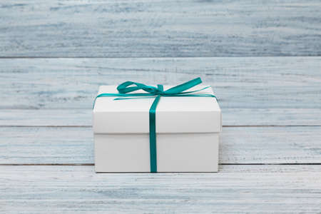 White gift box with green ribbon and bow over wood background with copy spaceの写真素材