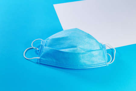 white sheet of paper and medical mask on blue background with copy space. Medical background, top viewの写真素材