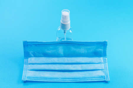 disposable medical surgical protective face mask with hands sanitizer on blue background. Protection against virus, coronavirus preventionの写真素材