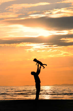 a loving father throwing his child on the shore of the beachの写真素材