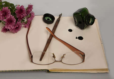 romantic flower next to glasses, ink and pen on opened notebookの写真素材