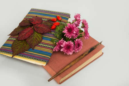 closed notebook and book with autumn leaves and flowersの写真素材