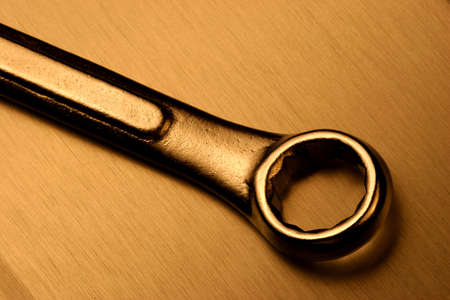 Steel wrench over a brushed steel surface with a warm light.の写真素材